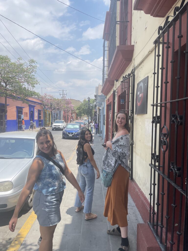 The author and two fellow students pictured together smiling and looking back at the camera on a sunny sidewalk in Oaxaca during the Semana Santa trip.