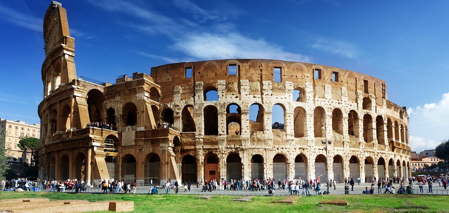 Panorama of the Roman Colosseum with tourists in the foreground.