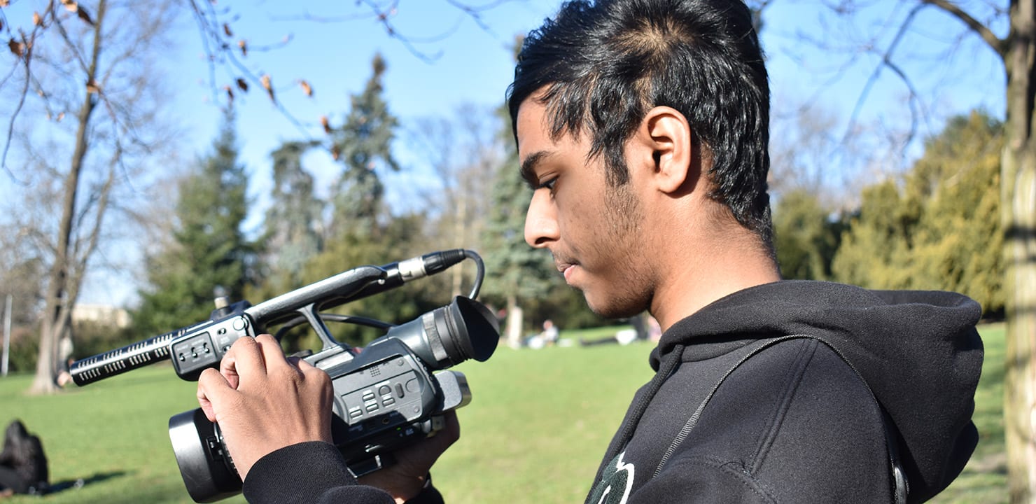 A student recording video footage with a professional camera.