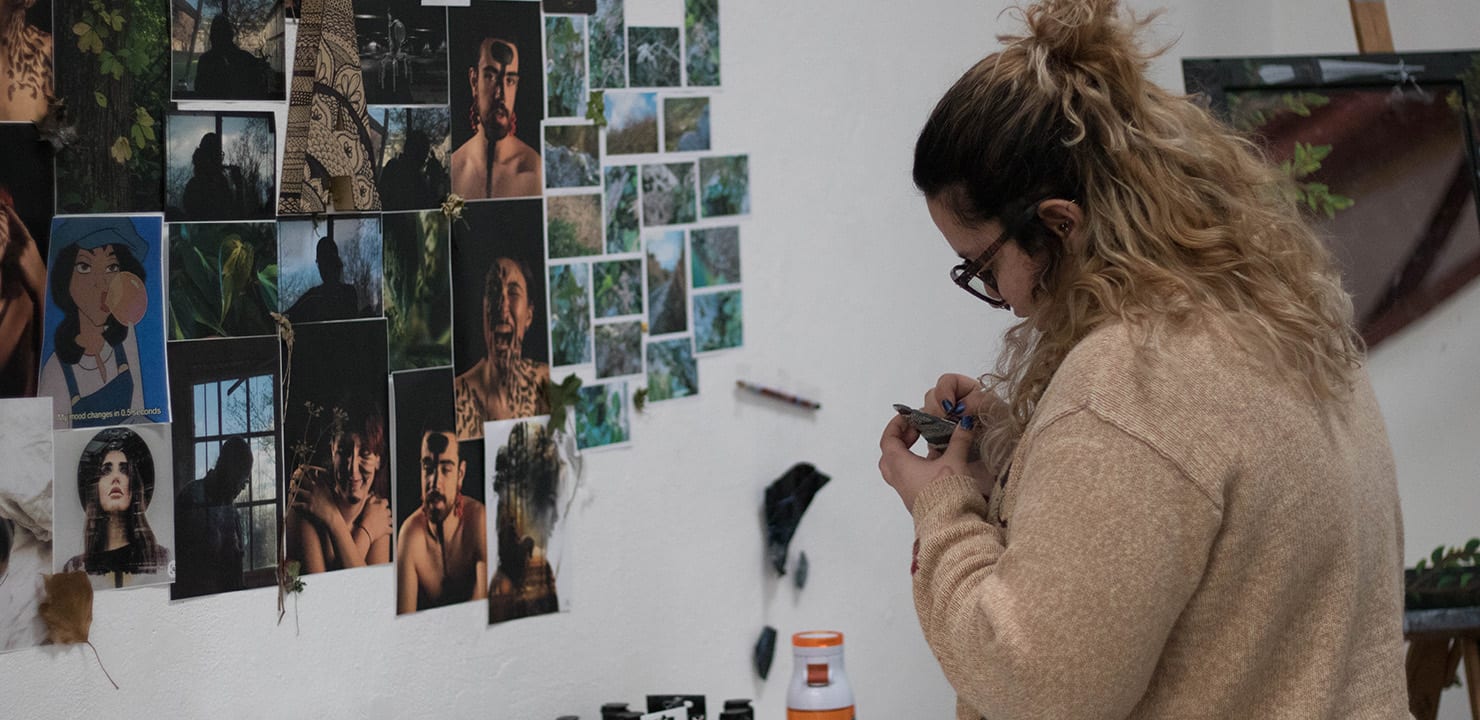 A student adding a series of photographs from a photo shoot onto a wall for review.